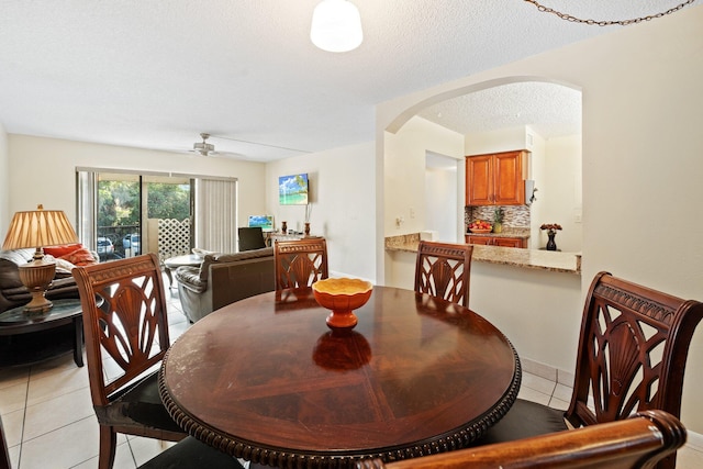 tiled dining room with ceiling fan and a textured ceiling