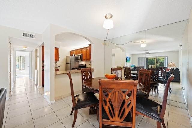 dining space featuring ceiling fan, light tile patterned floors, and a textured ceiling