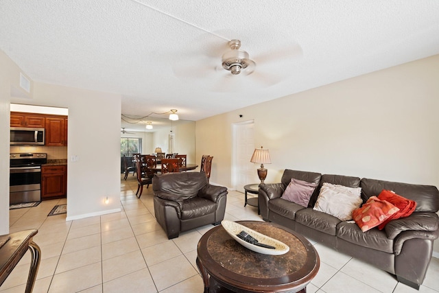 living room with ceiling fan, light tile patterned floors, and a textured ceiling