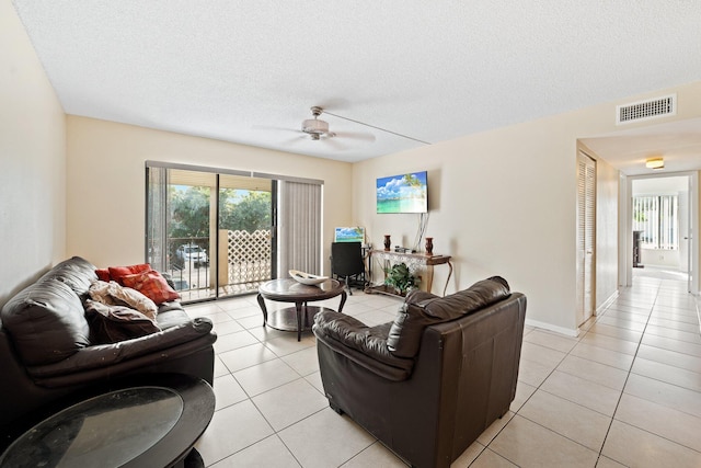 tiled living room with ceiling fan and a textured ceiling