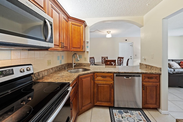 kitchen featuring appliances with stainless steel finishes, stone countertops, light tile patterned floors, and sink