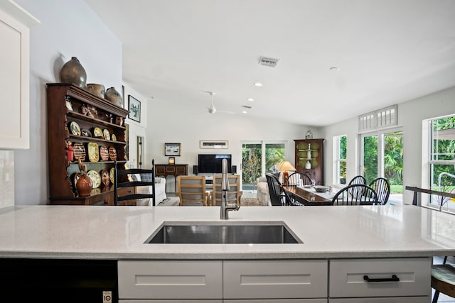 kitchen with white cabinets, sink, vaulted ceiling, and a wealth of natural light