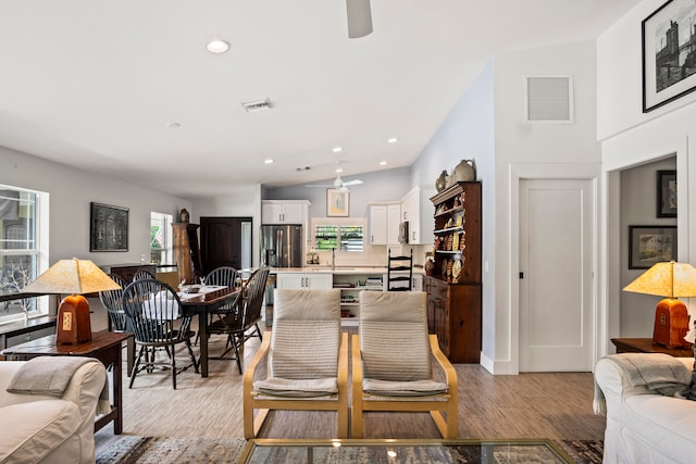 living room with lofted ceiling, sink, ceiling fan, and light hardwood / wood-style flooring