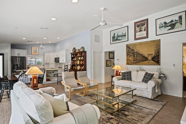 living room with ceiling fan, light wood-type flooring, and high vaulted ceiling