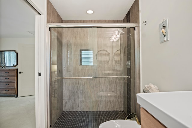 bathroom featuring a shower with door, vanity, and toilet