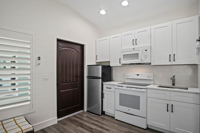 kitchen featuring dark hardwood / wood-style floors, sink, lofted ceiling, white cabinetry, and white appliances