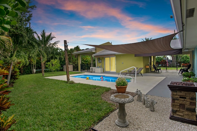 pool at dusk with a lawn and a patio