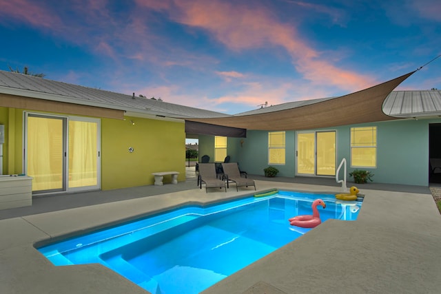 pool at dusk featuring a patio area