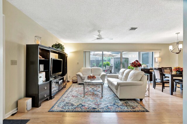 living room featuring a textured ceiling, ceiling fan with notable chandelier, and light hardwood / wood-style flooring