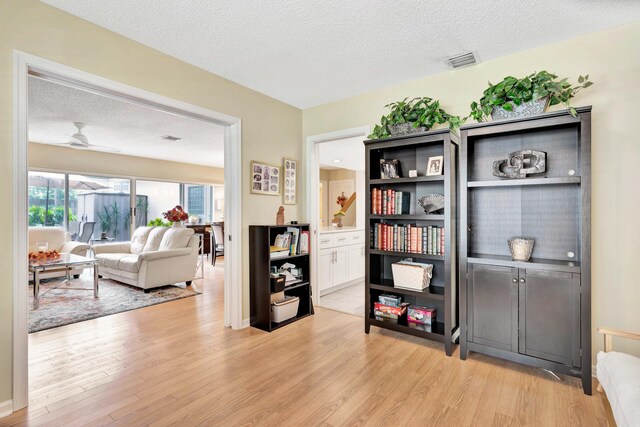 interior space with ceiling fan, a textured ceiling, and light wood-type flooring