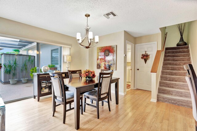 dining area featuring light wood-type flooring, a chandelier, and a textured ceiling