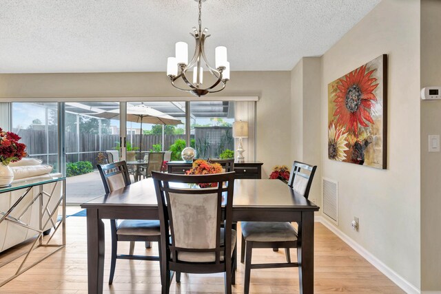 dining space with a notable chandelier, light hardwood / wood-style floors, plenty of natural light, and a textured ceiling