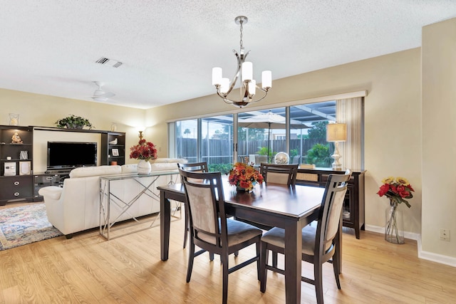 dining area featuring a textured ceiling, ceiling fan with notable chandelier, and light hardwood / wood-style floors