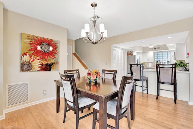 dining space with light hardwood / wood-style flooring and an inviting chandelier