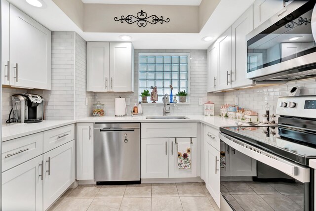 kitchen with sink, white cabinetry, decorative backsplash, appliances with stainless steel finishes, and light tile patterned floors