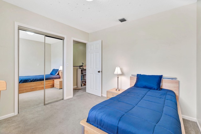 bedroom with a closet, light colored carpet, and a textured ceiling