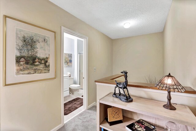 corridor with light colored carpet and a textured ceiling