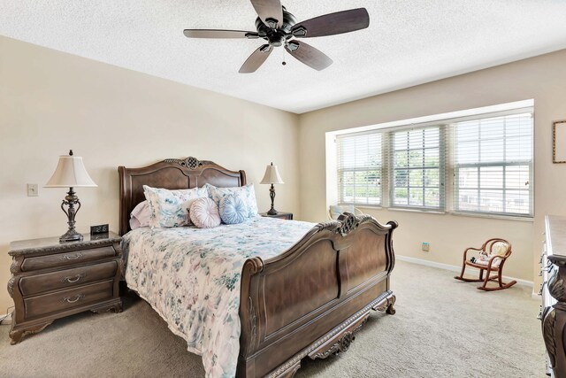 carpeted bedroom featuring ceiling fan and a textured ceiling