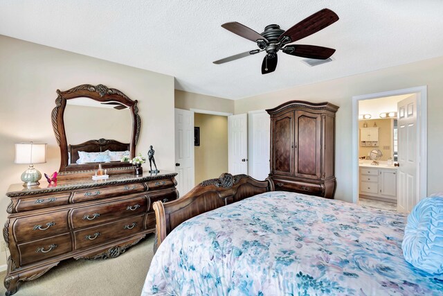 bedroom featuring light carpet, connected bathroom, ceiling fan, and a textured ceiling