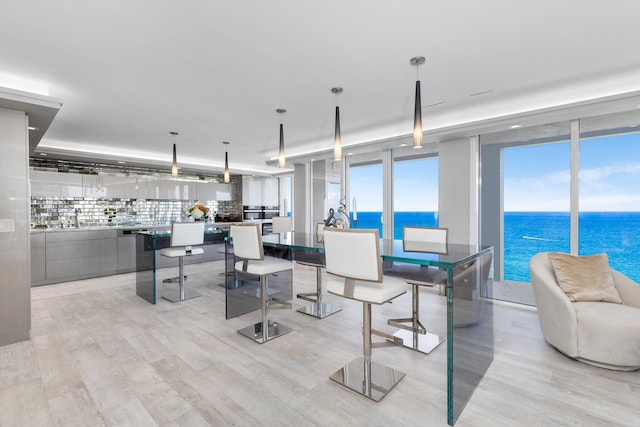 dining space with a water view and light hardwood / wood-style floors