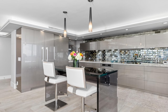 kitchen featuring backsplash, gray cabinetry, hanging light fixtures, and light hardwood / wood-style flooring