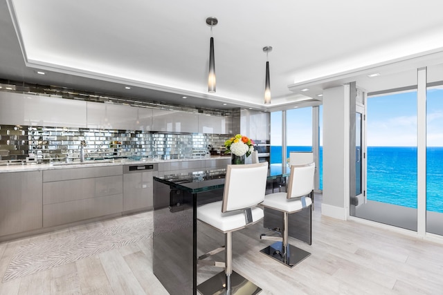 kitchen featuring decorative backsplash, a water view, plenty of natural light, and hanging light fixtures