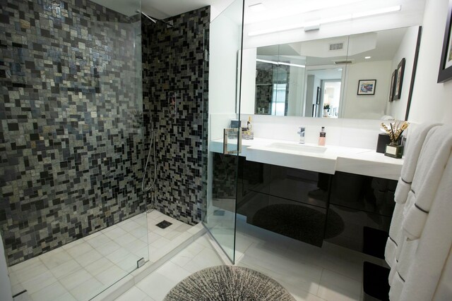 bathroom featuring tile patterned flooring, vanity, a shower with shower door, and tile walls