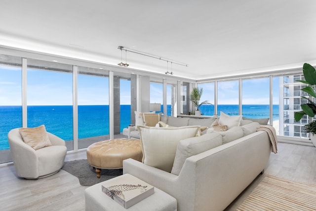 living room with expansive windows, a water view, light wood-type flooring, and rail lighting