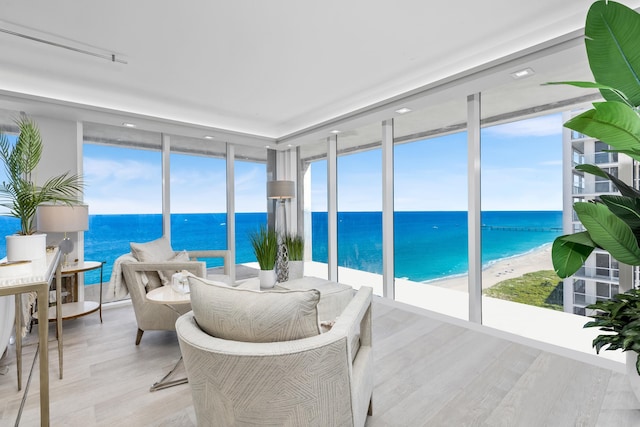 sunroom / solarium featuring a water view and a view of the beach