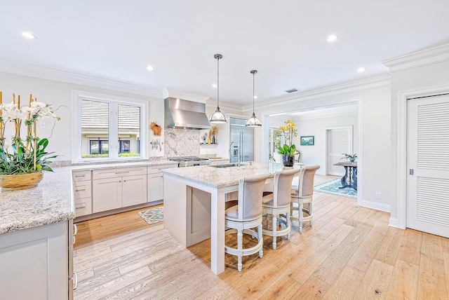 18587 SE Ferland Ct, Jupiter, FL 33469 - kitchen featuring light wood finished floors, ornamental molding, wall chimney exhaust hood, a sink, and built in refrigerator