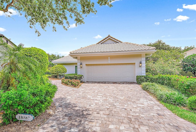 18587 SE Ferland Ct, Jupiter, FL 33469 - view of front facade with a tile roof, decorative driveway, an attached garage, and stucco siding