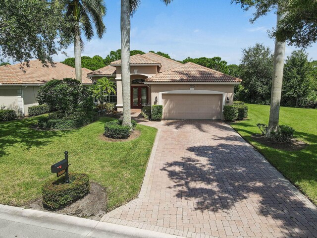 view of front of house featuring an attached garage, a front lawn, stucco siding, french doors, and a tiled roof