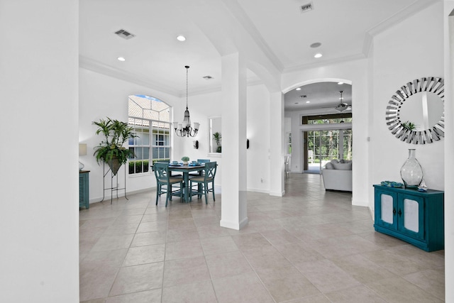 interior space with crown molding, arched walkways, visible vents, and ceiling fan with notable chandelier