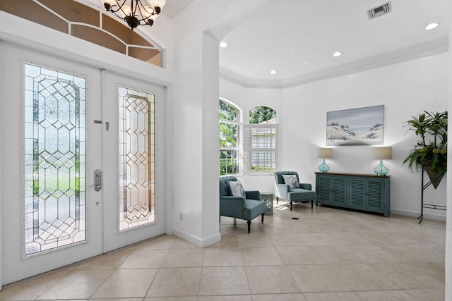 tiled entrance foyer with french doors, an inviting chandelier, and crown molding