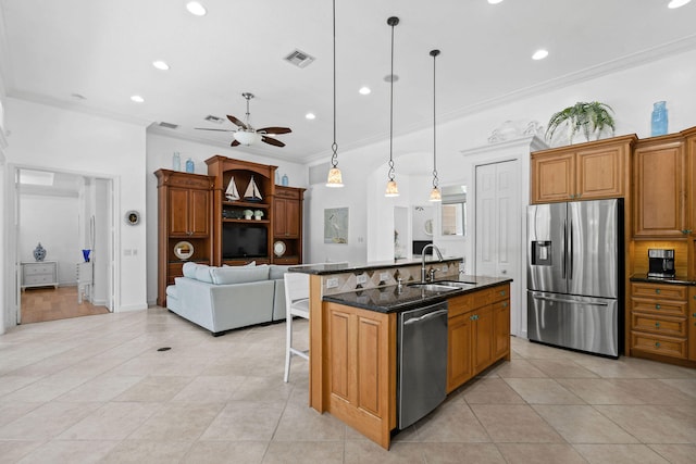 kitchen featuring ceiling fan, decorative light fixtures, a center island with sink, appliances with stainless steel finishes, and crown molding