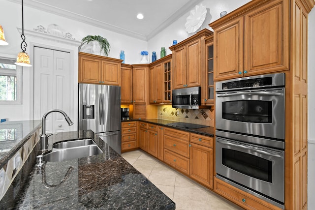 kitchen with sink, hanging light fixtures, appliances with stainless steel finishes, crown molding, and dark stone countertops