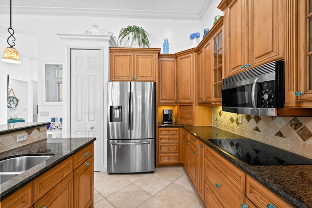 kitchen featuring dark stone countertops, light tile patterned flooring, stainless steel appliances, crown molding, and decorative light fixtures