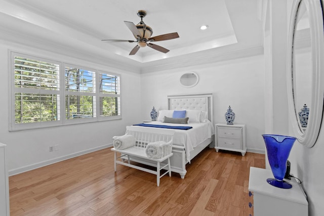 bedroom with crown molding, light wood-style floors, baseboards, recessed lighting, and a raised ceiling