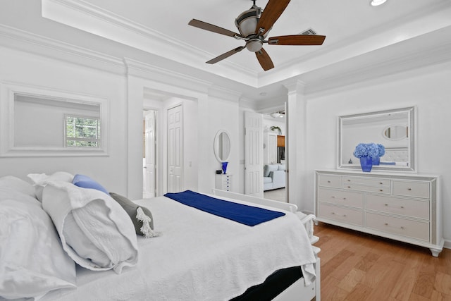 bedroom featuring ornamental molding, a tray ceiling, light hardwood / wood-style floors, and ceiling fan