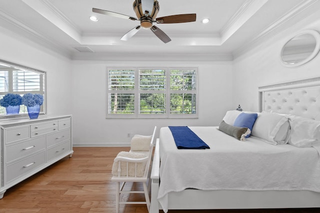 bedroom featuring ceiling fan, a raised ceiling, light wood-type flooring, and ornamental molding