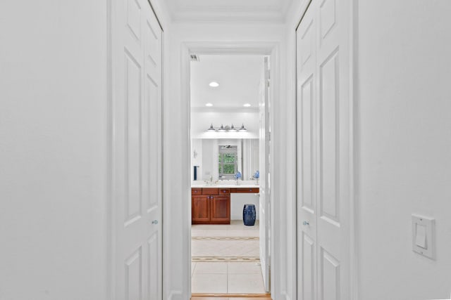 corridor featuring ornamental molding and light tile patterned floors