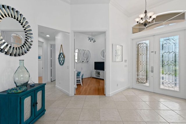 tiled foyer with a notable chandelier, a healthy amount of sunlight, and crown molding