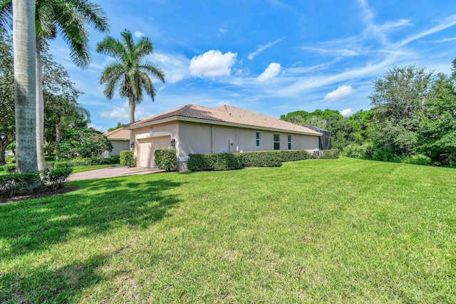view of side of property featuring a lawn, stucco siding, an attached garage, driveway, and a tile roof