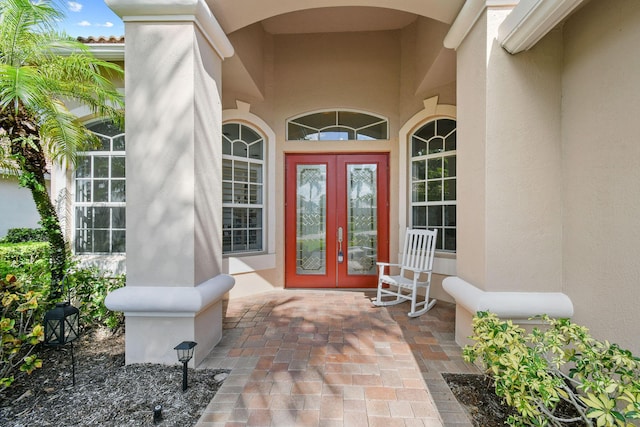 view of exterior entry featuring french doors and stucco siding