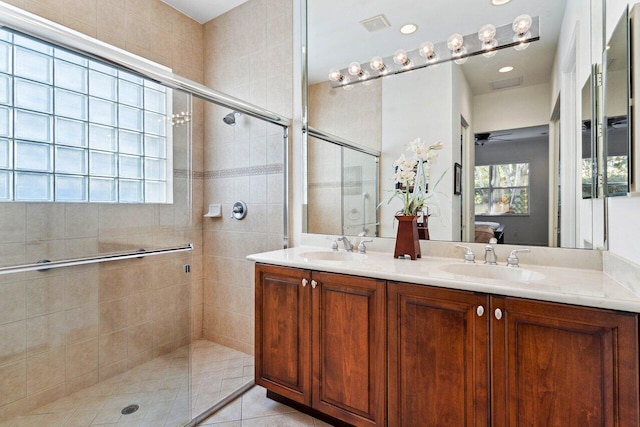 bathroom featuring a shower with shower door and vanity