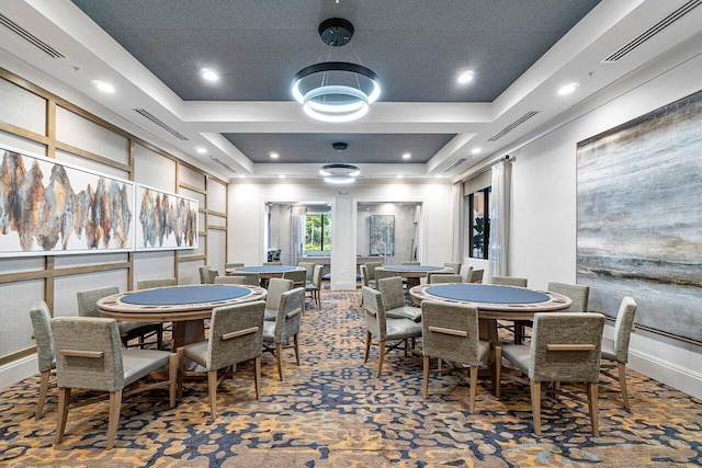 dining area with a raised ceiling and carpet