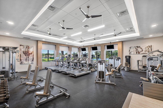 exercise room with ceiling fan and a raised ceiling