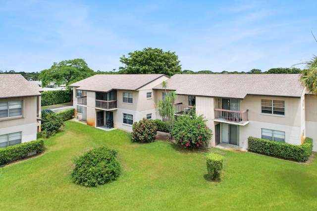 rear view of property with a lawn and a balcony