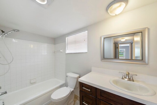 full bathroom featuring tiled shower / bath, vanity, and toilet