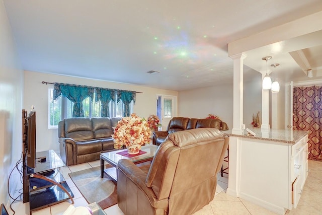 living area featuring light tile patterned floors, visible vents, and decorative columns